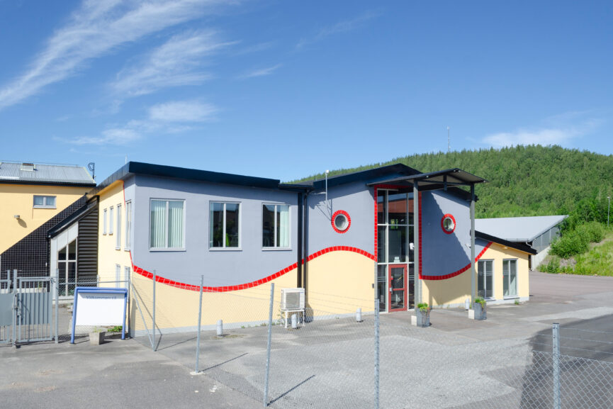Gulgrå två-vånings kontorsbyggnad med röda detaljer